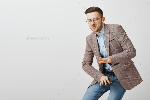 Amused good-looking stylish guy being carried away with cool music bending down in dance move