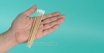 Cotton sticks for swab in hand on mint green or Tiffany Blue background.covid-19 concept