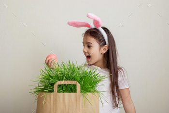 A beautiful little girl with hare ears, holds a pink egg