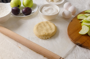 Woman making dough for homemade apple and plum galette, closeup