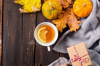 Autumn still life with cup of tea, pumpkins and leaves on wooden background