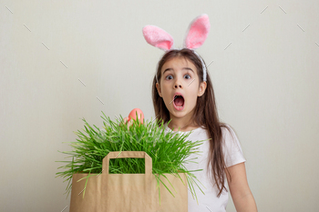 A surprised little girl with hare ears, holds a pink egg