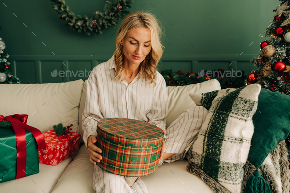 A woman in pajamas opens Christmas gifts. - Stock Photo - Images