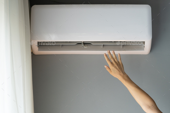 Woman stretches hand to catch stream of air and tries to warm up apartment to feel better