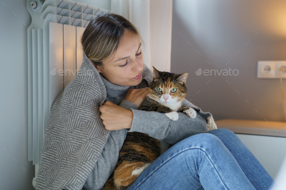 Young woman covered with warm blanket feels better hugging domestic cat and tries to continue life