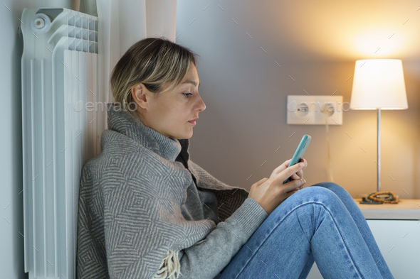 Tired blonde woman snuggling up to battery scrolls smartphone looking for vacancies via Internet