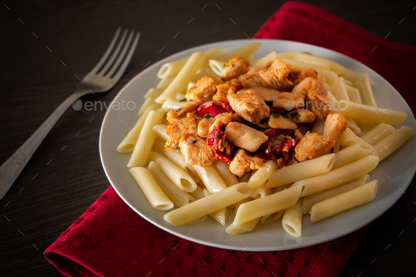 Penne pasta with chicken and vegetables in tomato sauce Stock Photo by
