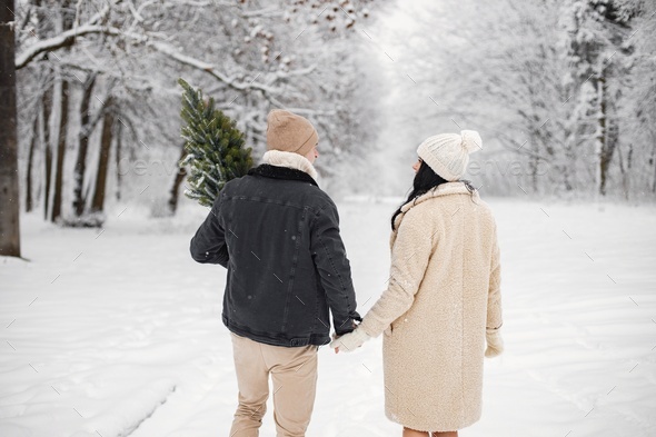 Backside portrait of romantic couple walking in forest at winter day ...