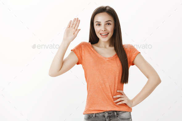 Hi remember me. Portrait of positive friendly caucasian female model in orange t-shirt, holding hand