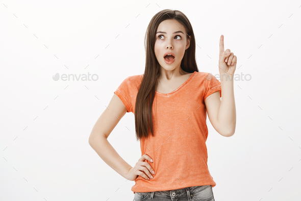 What if. Creative excited caucasian female student, raising index finger and looking up, dropping