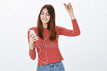 Checking out trending music in smartphone app. Portrait of party girl with joyful mood, holding