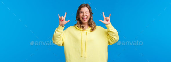 Let us have fun. Carefree joyful good-looking blonde female in yellow hoodie show rock-n-roll sign