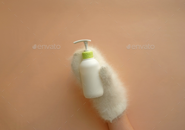 Cosmetic pump bottle of moisturizing lotion hold hands in mittens.