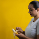 latin woman opening banana to eat, on yellow background - PhotoDune Item for Sale