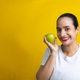 Latin woman with green apple in hand very happy, in yellow background - PhotoDune Item for Sale