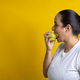 Latin woman biting green apple, in yellow background - PhotoDune Item for Sale