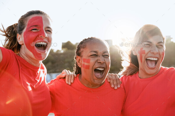 Multiracial senior football sport fans celebrate while watching soccer match game inside the crowd