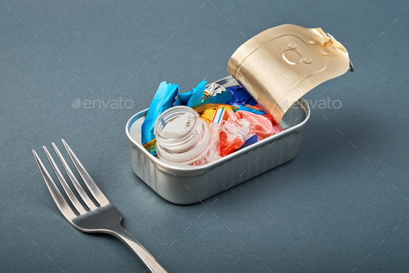 Open tin can and fork. Plastic waste instead of fish inside. Ocean plastic pollution concept