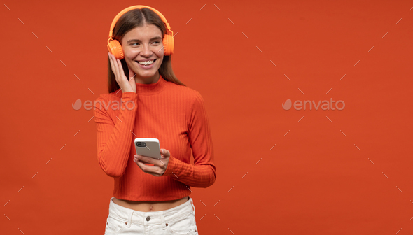 Woman testing online media player listening to favorite music in wireless headphones using phone