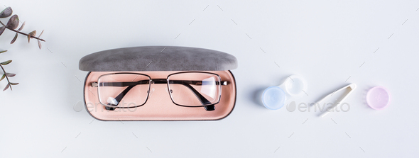 A case with glasses, an open container with contact lenses and tweezers. Top view. Web banner