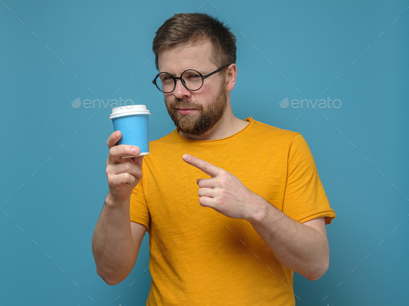 Man points with index finger to a paper, disposable cup that he holds in hand