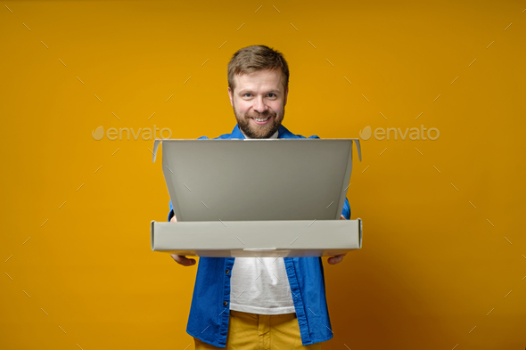 Joyful man came to a meeting with friends with a pizza, he smiles and holds out an open box