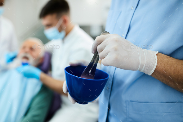 Close up of dental assistant mixing material for dental impression.