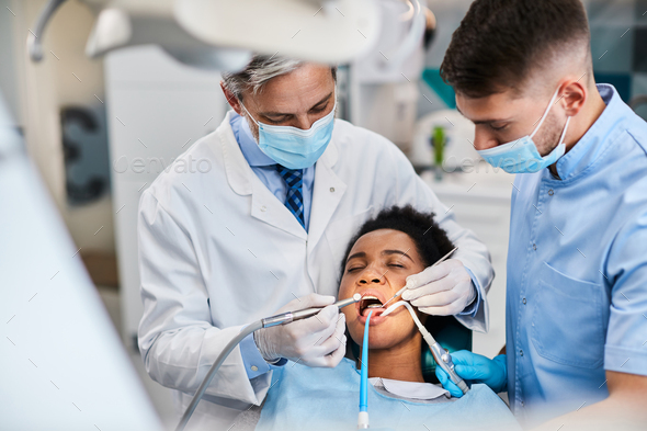 African American woman having dental drill procedure at dentist\'s office.