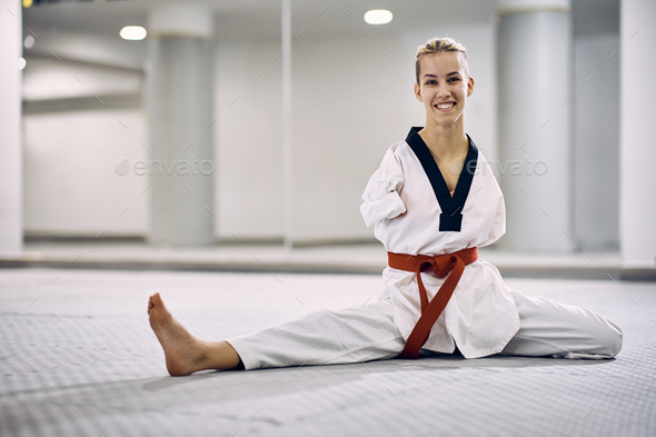 Happy female martial arts athlete with disability warming up while exercising in health club.