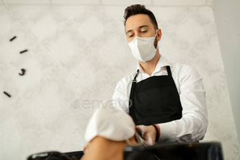 Below view of hairstylist with face mask washing customer's hair at the salon.