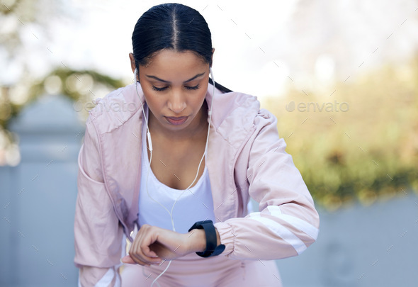I can do better. Shot of a sporty young woman checking her watch while exercising outdoors.