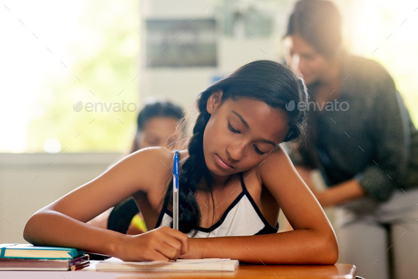 Getting a head start on her homework. Shot of a young schoolgirl doing her homework in class.