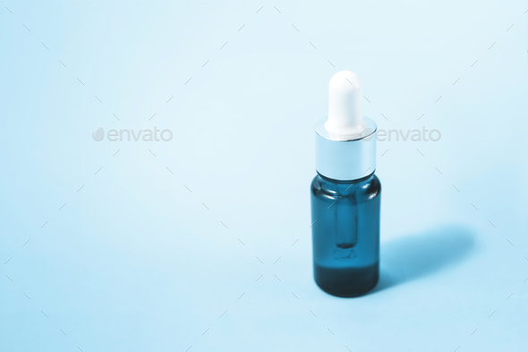 A glass dropper bottle on the blue background.
