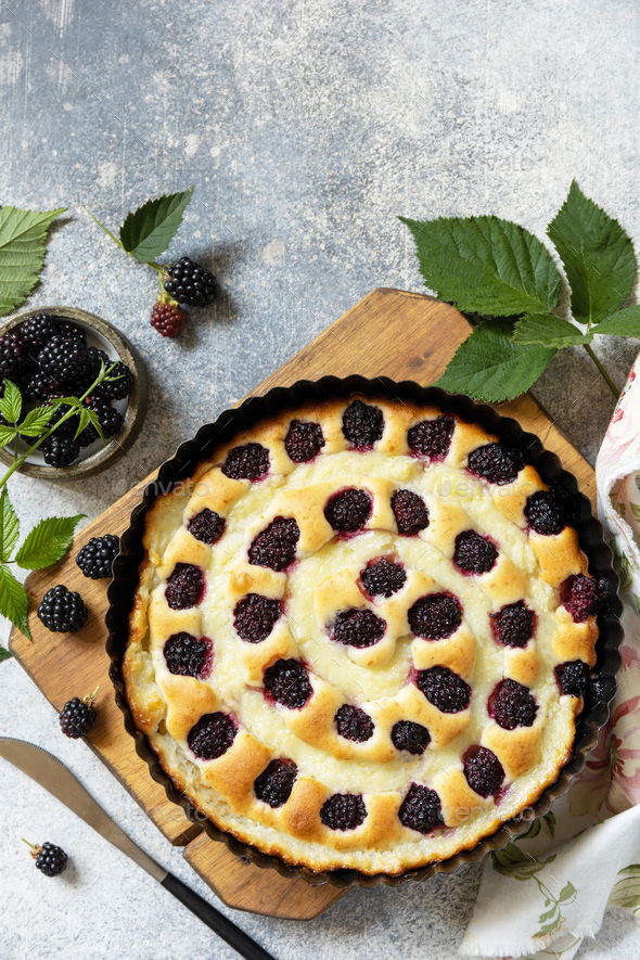 Vegan gluten-free pastry. Sweet pie with blackberry and custard on stone tabletop.
