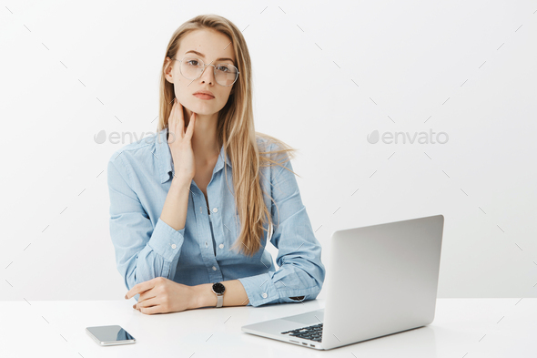 Successful female entrepreneur in glasses and blue-collar shirt touching neck as sitting tired near