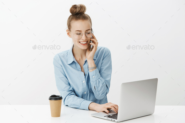 Portrait of polite and assertive attractive female manager working in office answering cold call via