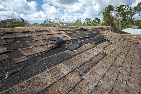 Damaged house roof with missing shingles after hurricane Ian in Florida ...