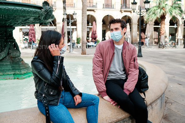 Two friends wearing a face mask while talking outdoors