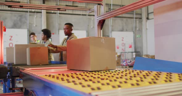 Diverse male and female workers with boxes on conveyor belt in warehouse alt