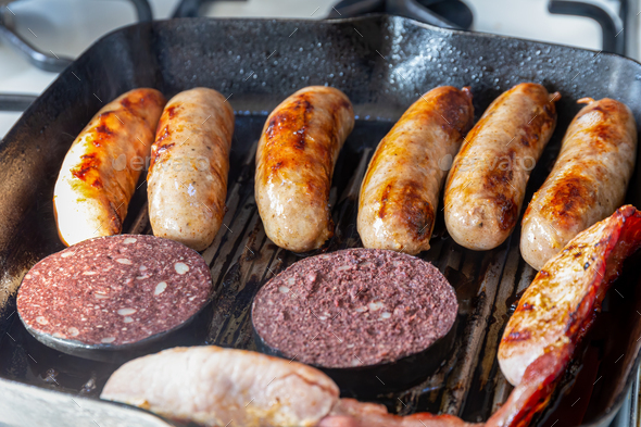 Sausages, bacon and black pudding cooking in a griddle pan