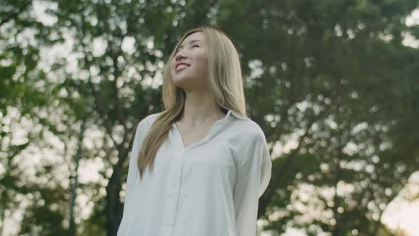 Asian female looking around her enjoying the breeze in the public park during a beautiful sunset.