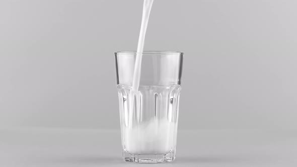 Milk Pouring Into Faceted Glass Close Up Isolated on Light Grey Background alt