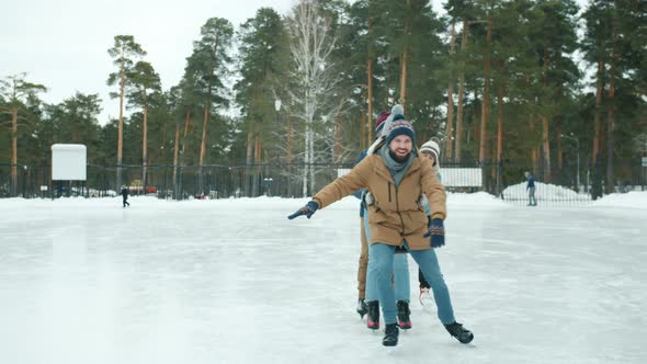 Happy Youth Girls and Guys Ice-skating at Frozen Lake in Park Having Fun Laughing alt