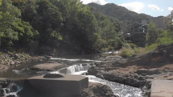 Aerial shot slowly rising above river and going upstream in Jozankei famous onsen hot spring town Ho alt