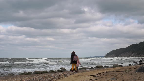 Woman and little girl walk on beach
