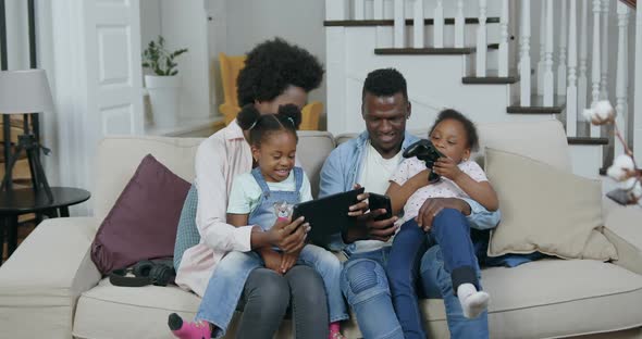 African American Family at Home while Revisioning Funny Videos on Tablet PC alt