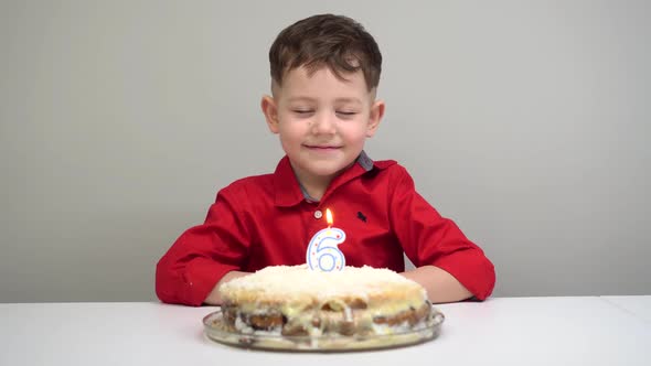Happy Little Kid Boy Celebrating His Birthday and Blowing Candles on Homemade Baked Cake, Indoor.