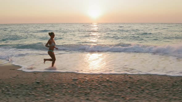 Aerial Low Altitude Follow View of Woman Running Along the Milos Beach of Lefkada Ionian Island alt