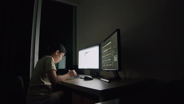 A young woman writes an article on a tablet at night in a home office.