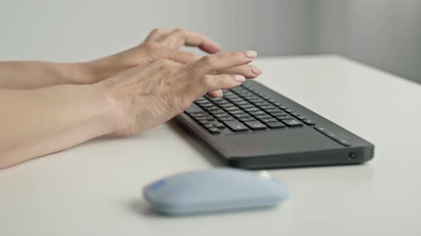 Female Hands Typing on Keyboard and Holding Computer Mouse on Light Background